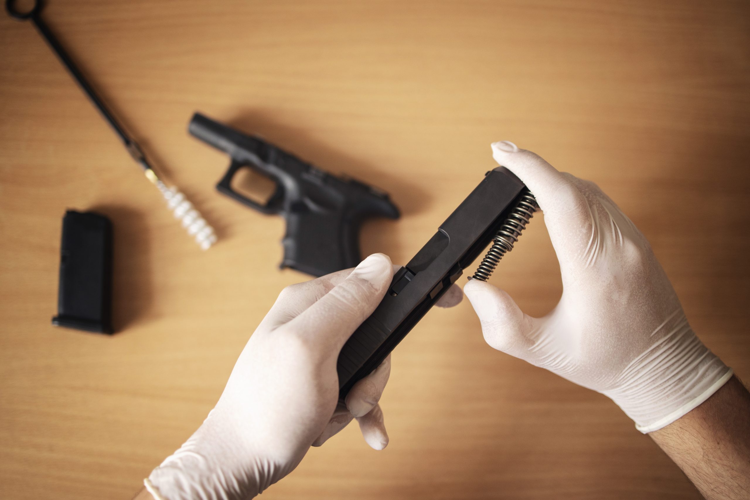 handgun disassembled into parts brush cleaning gunpowder residue scaled